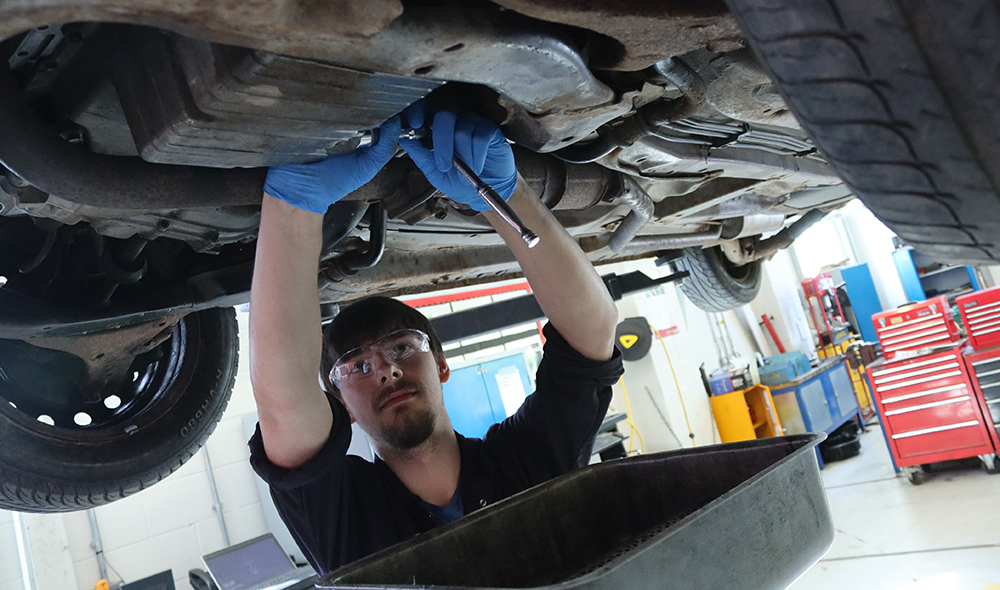 Motor vehicle student servicing a car.