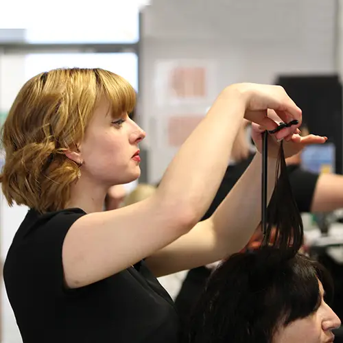 Hairdressing student cutting hair