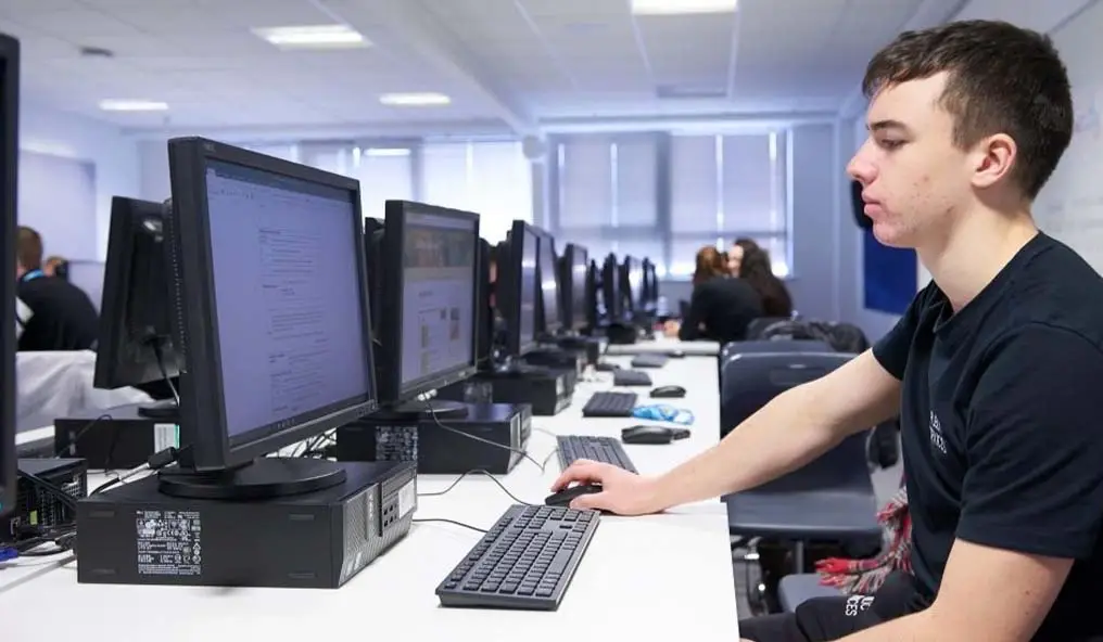 Male student sat at a computer terminal in a computer room