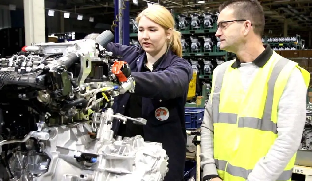 Female apprentice and her tutor working on a car engine