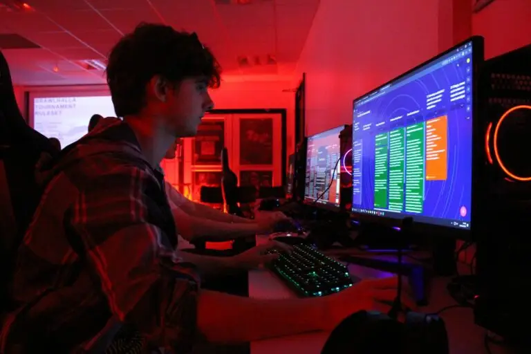 media and games student sat at a computer with the room lit in red lighting